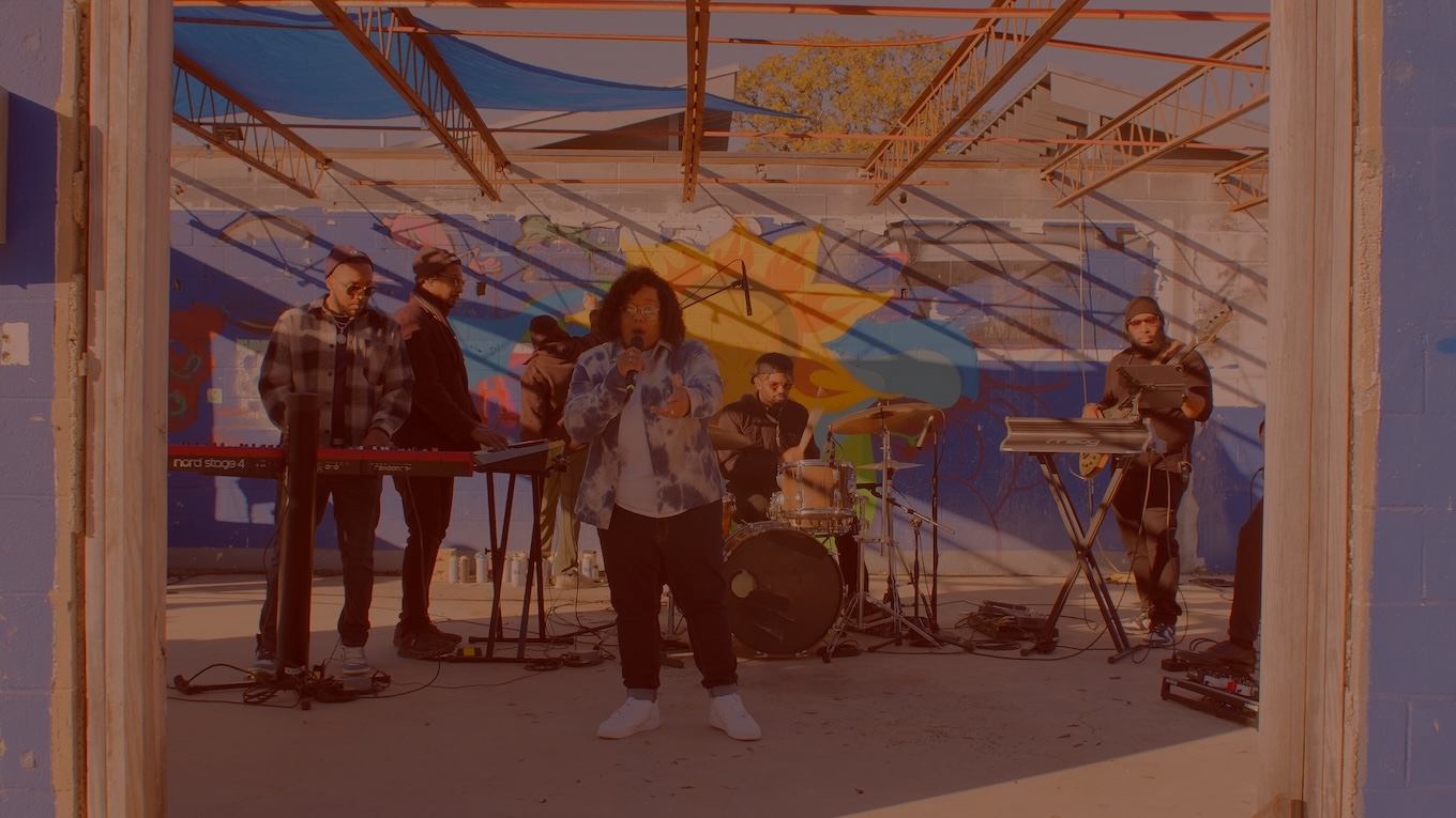 Recording artist, Mama Duke, performing in front of a live band with a colorful background.